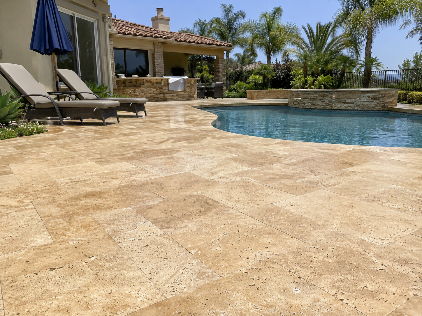 Wide shot of a freshly cleaned and sealed travertine pool deck in a San Diego backyard, showing rich stone color and a glare-free finish
