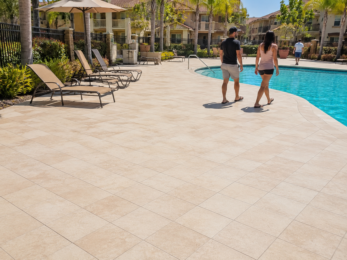 Wide shot of a clean, freshly restored tile pool deck at a San Diego HOA community, showing residents walking safely on slip-resistant flooring
