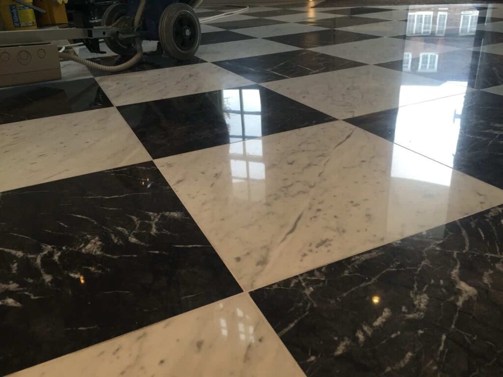 Floor machine polishing a black and white marble floor to a mirror finish during stone restoration